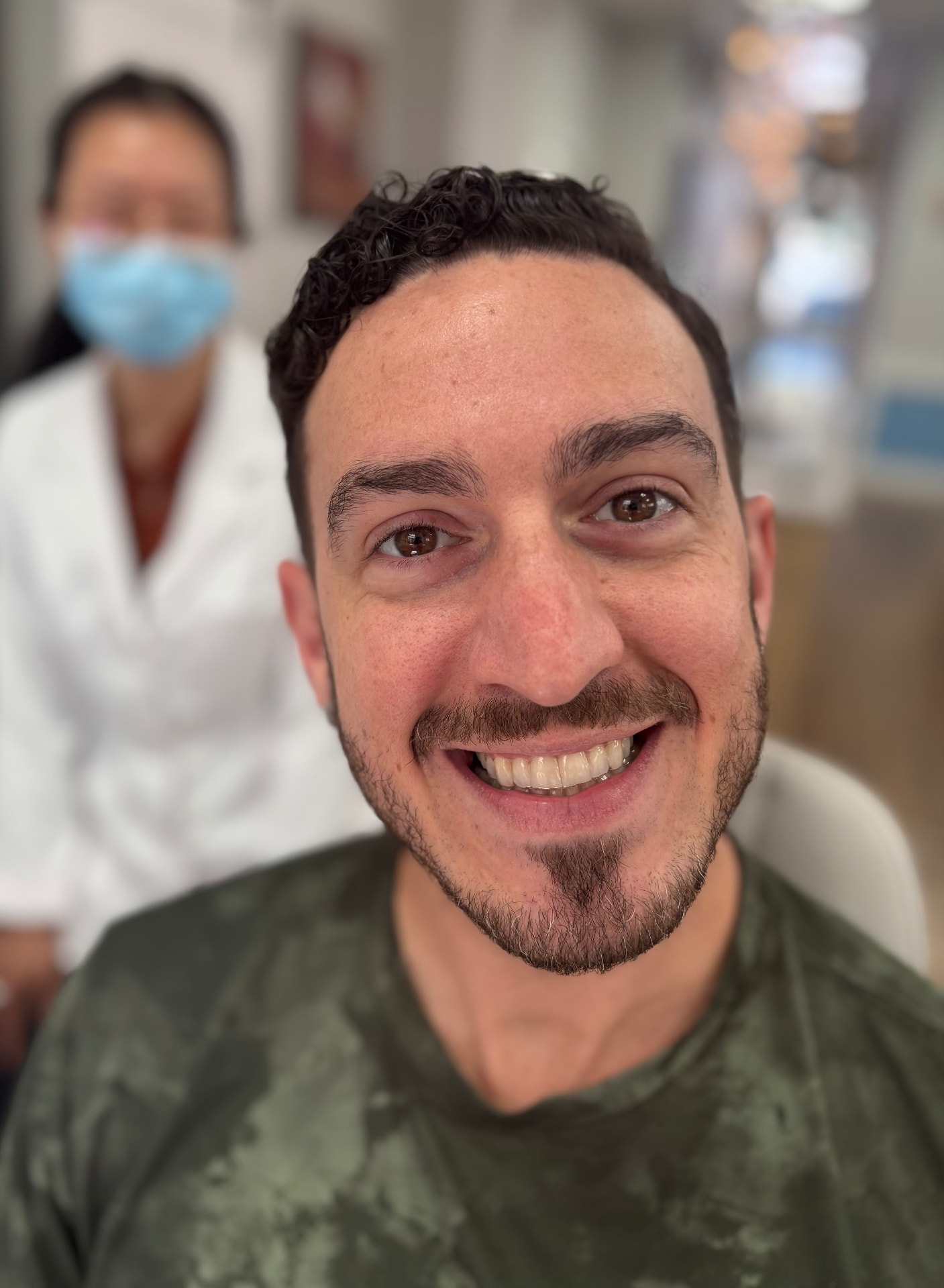 Adult orthodontic patient smiling with a team member behind him inside the office